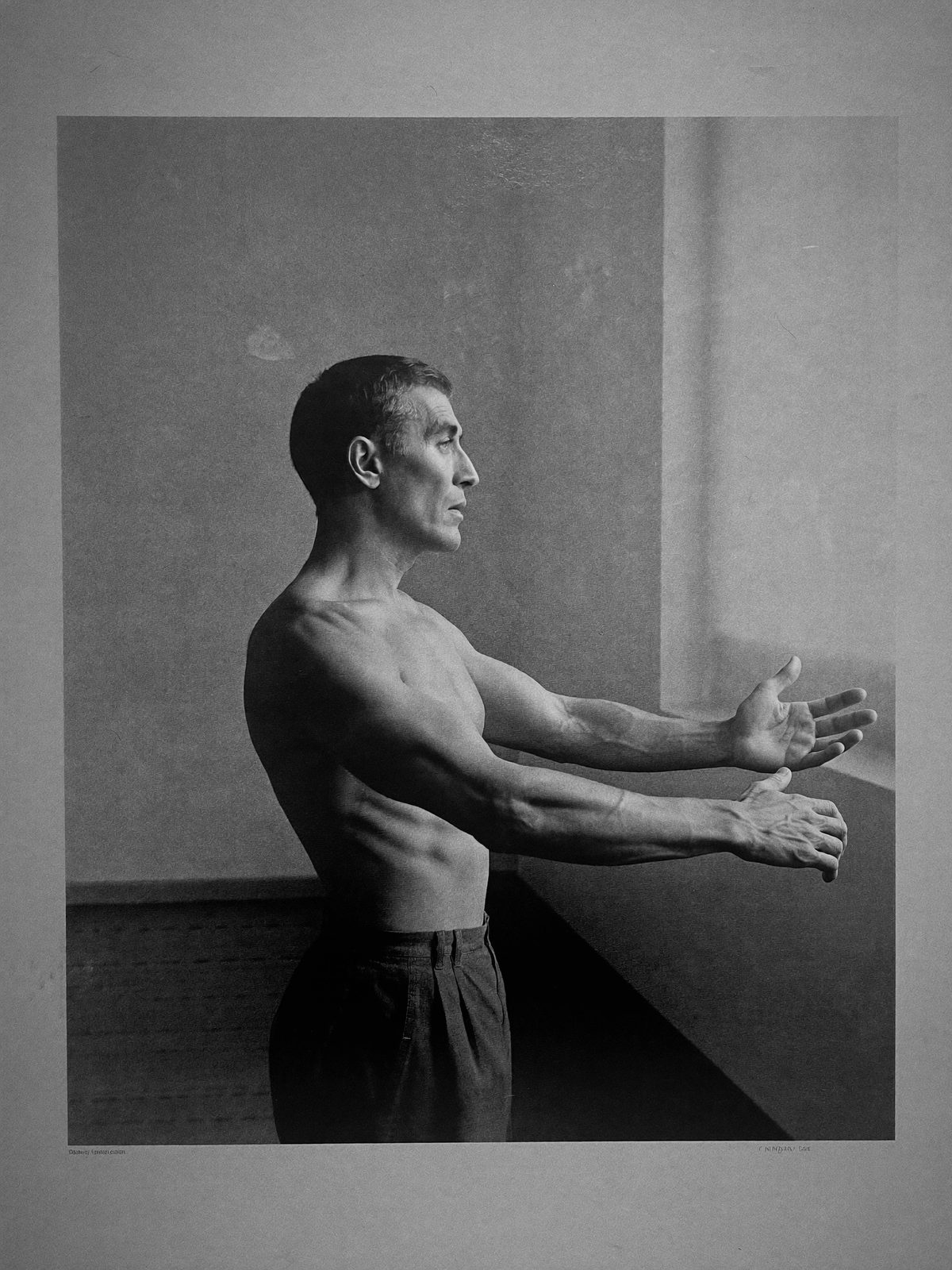 Homme mature de profil, ouvrant lentement les bras dans une lumière de fenêtre
