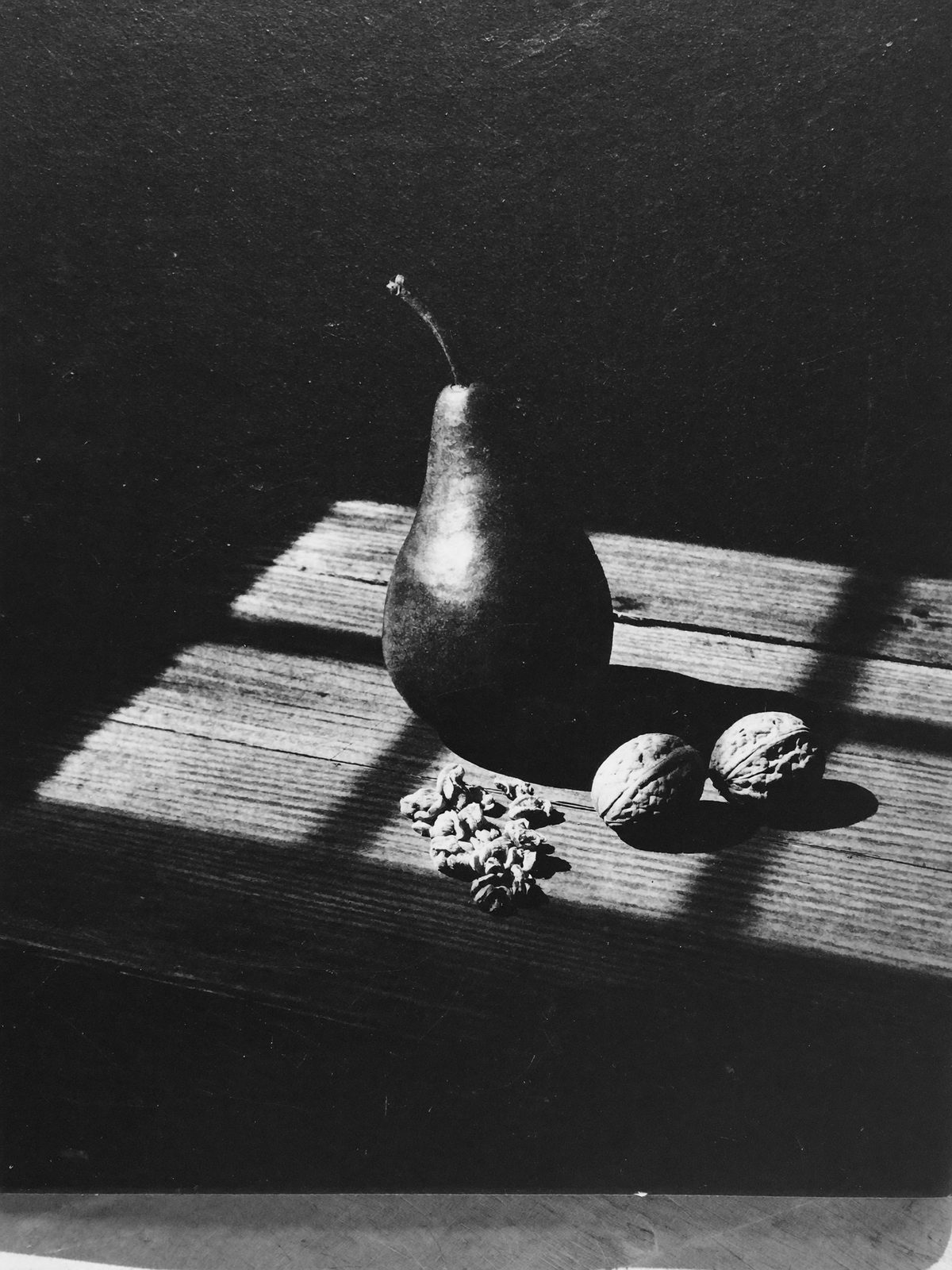 Poire et noix sur une table de bois brut, clair-obscur
