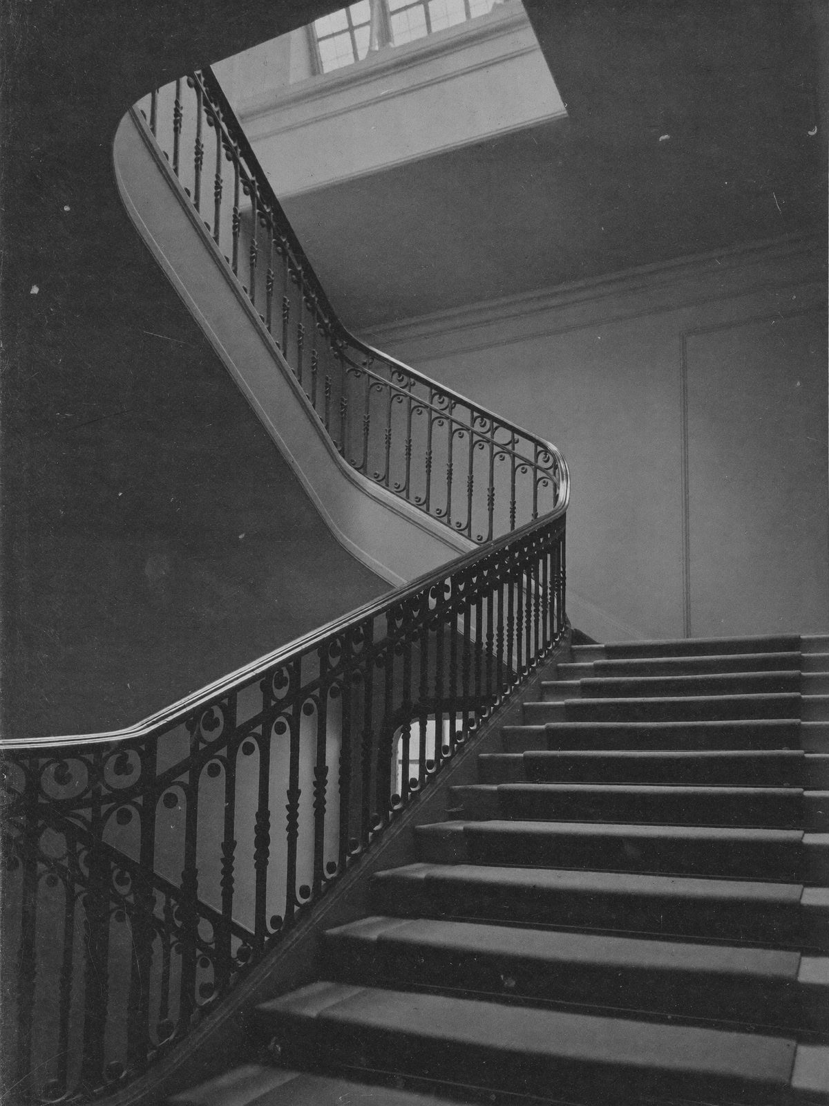 Escalier ancien montant vers le troisième étage, lumière zénithale