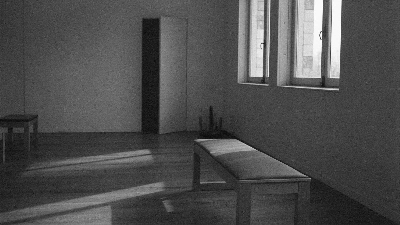 Studio calme : banc de bois, porte entrouverte, longues ombres